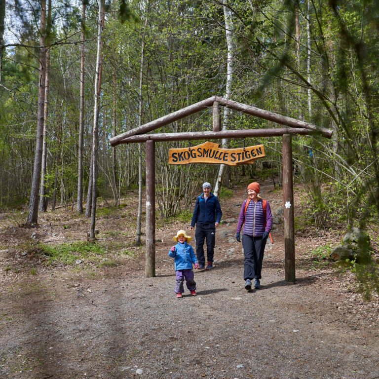 två vuxna med barn promenerar i naturen