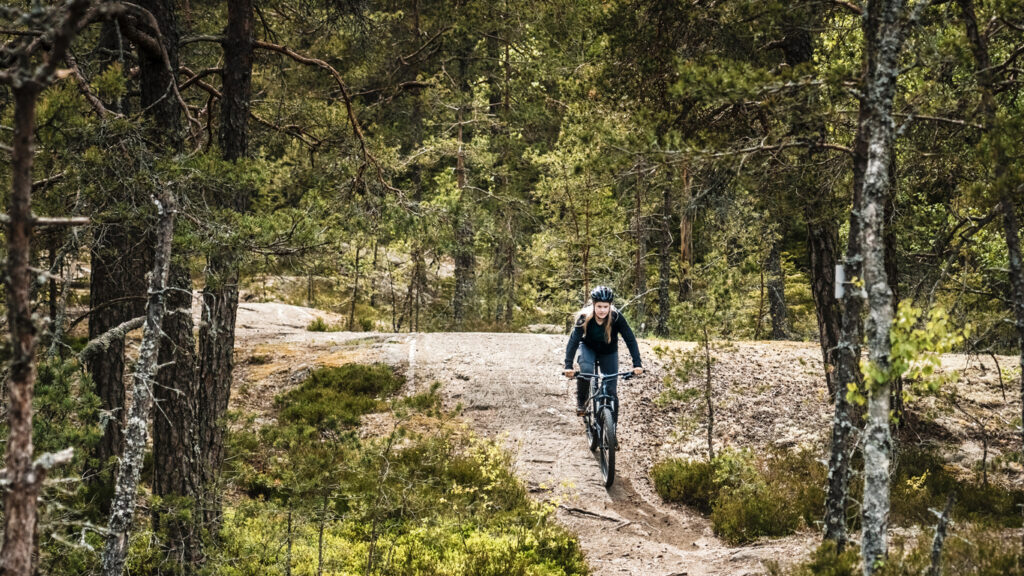 person som cyklar mountainbike i skogen
