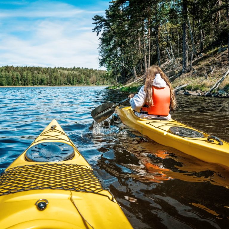 en person paddlar en gul kajakpå en sjö