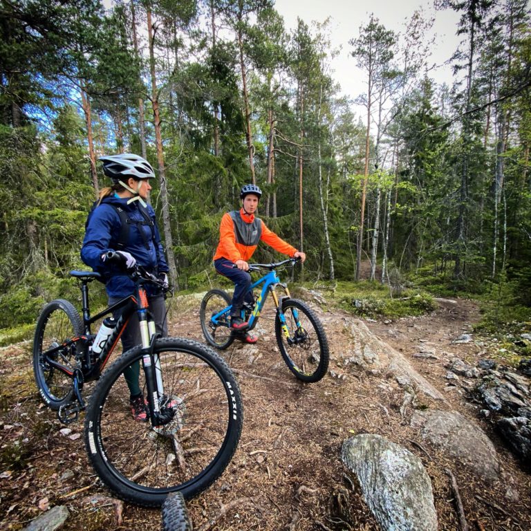 Två personer med cyklar i skogen