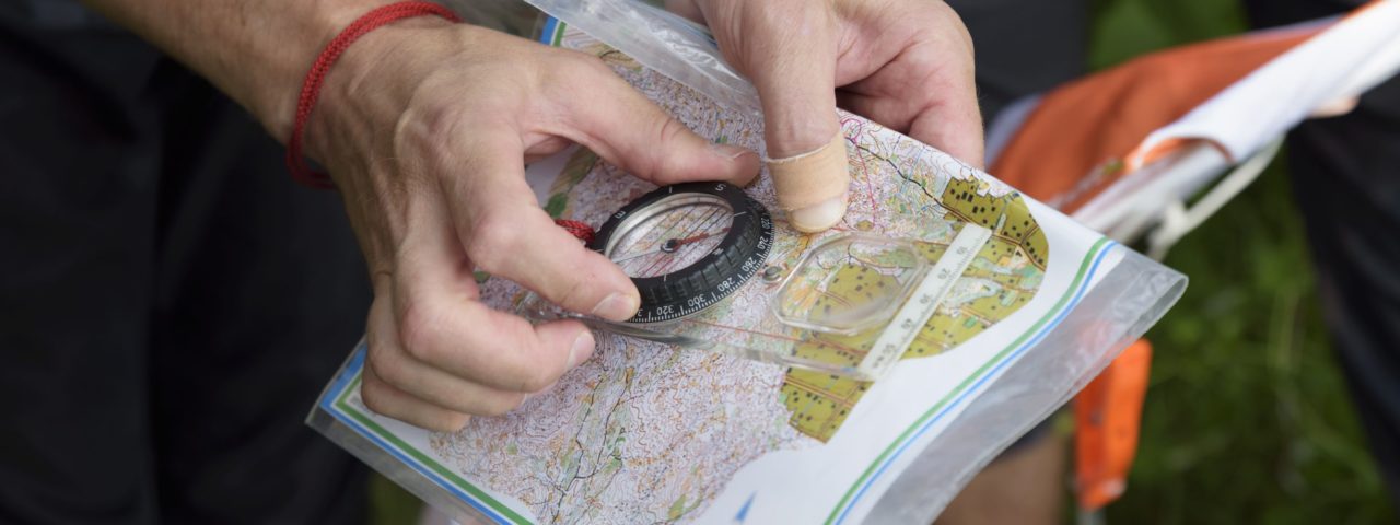 Person håller kompass och karta