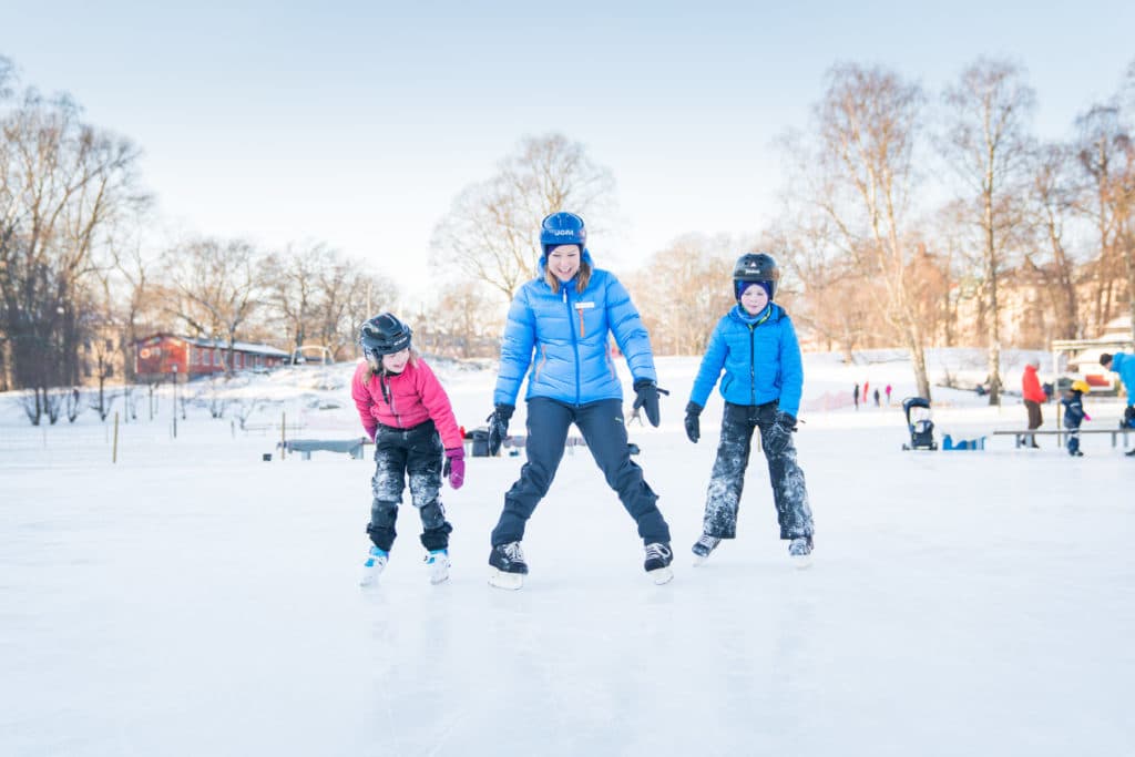barn med vuxen åker skridskor på isen