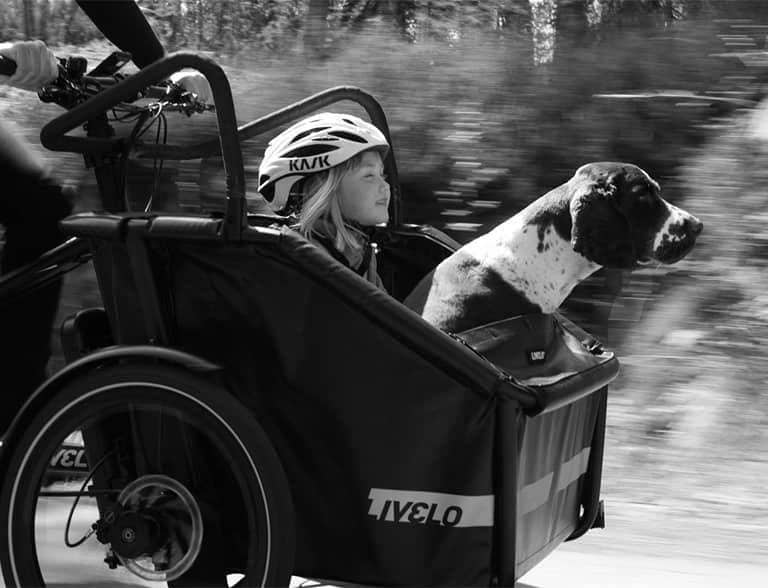 svartvit bild på barn och hund sitter i en lådcykel