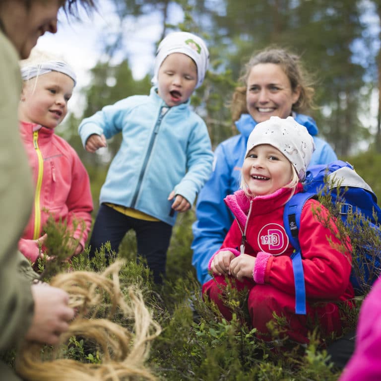 glada barn i färgglada kläder lyssnar på skogsmullei skogen