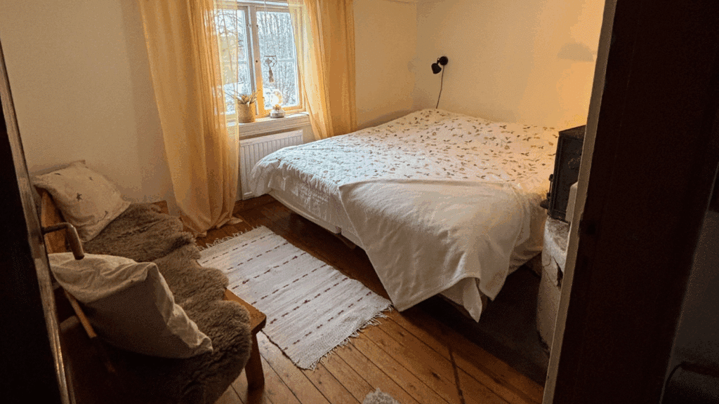 Ett ombonat sovrum med en dubbelsäng och två fåtöljer.