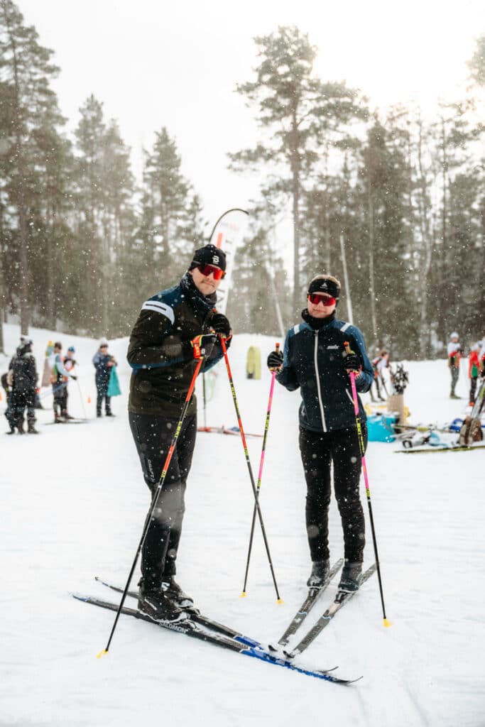 Två längdskidåkare poserar framför kameran.