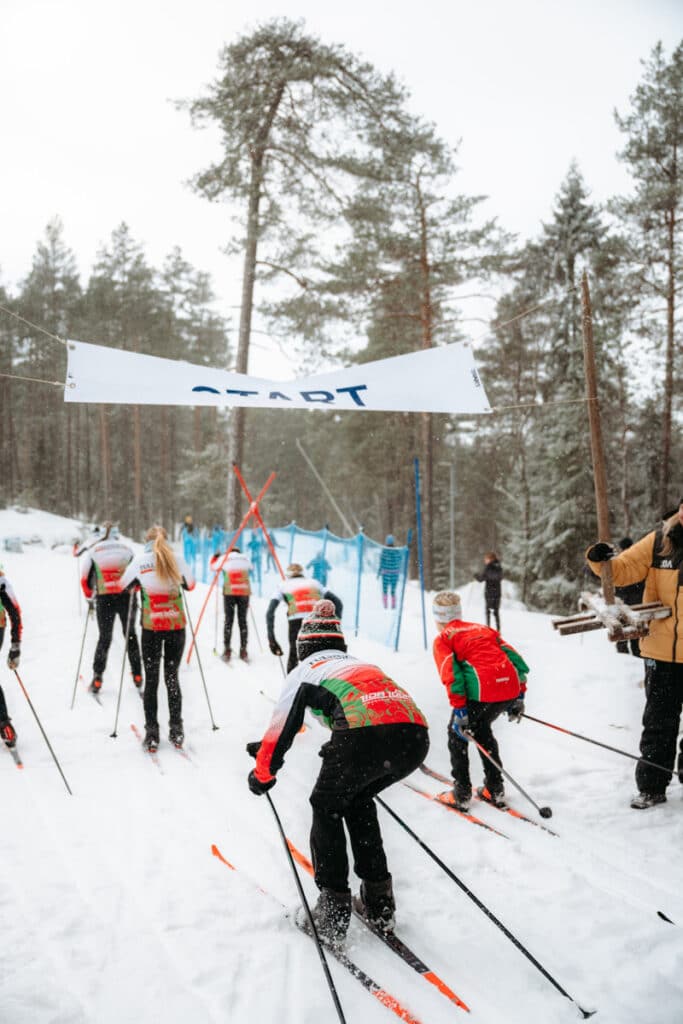 En grupp människor som åker längdskidor under en "Start"-vepa.