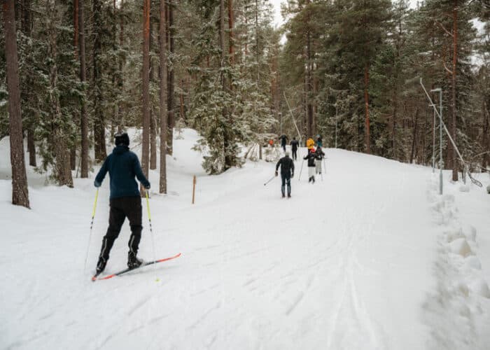 Människor åker i längdskidspår i vinterandskap.