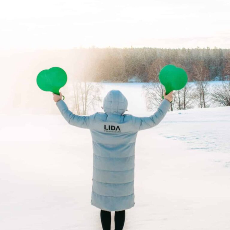 Person med vinterjacka som det står Lida på står med armarna utsträckta med två stjärtlappar i händerna.