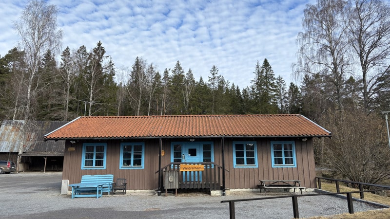 En brun byggnad med blå dörrar och ett rött tak.