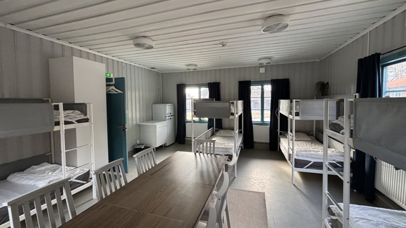 Ett rum med av våningssängar och ett långbord.