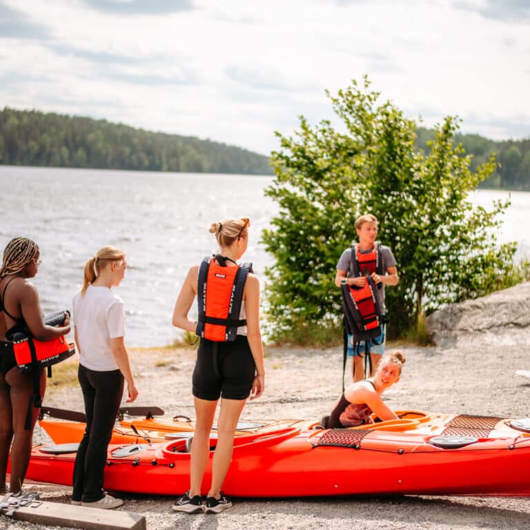 En grupp människor som står runt en röd kajak.