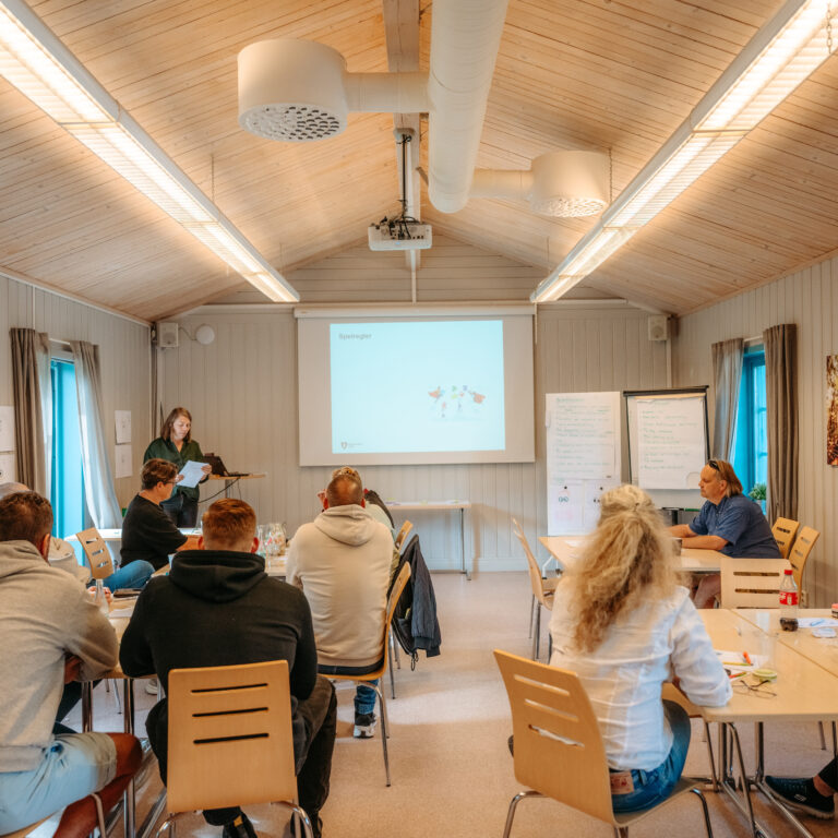 En grupp människor som sitter runt bord i ett rum.
