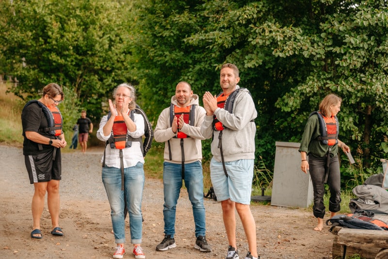 En grupp människor med flytvästar som står på en grusväg och klappar händerna.